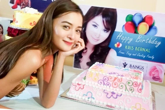Kris Bernal posing beside a birthday cake and celebratory backdrop