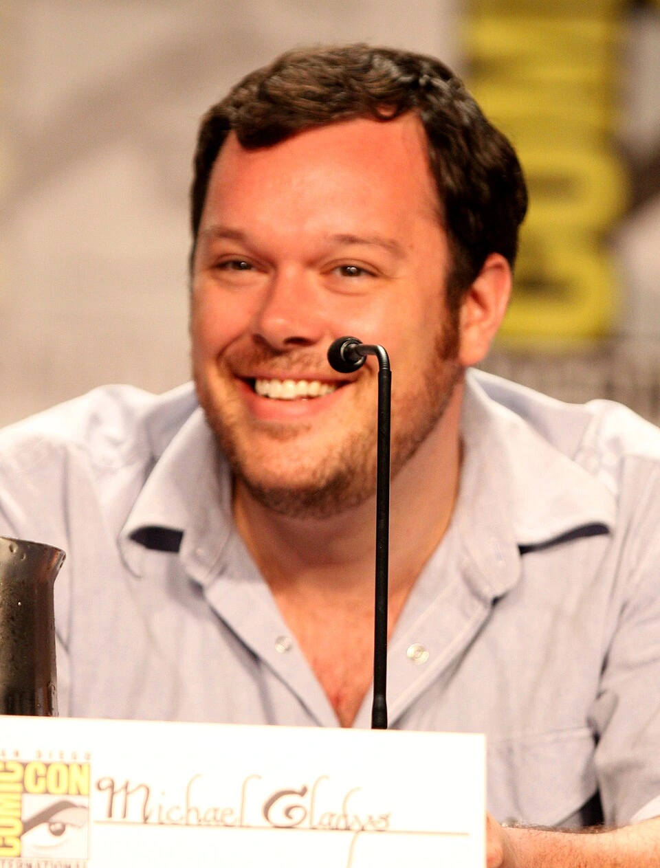 Michael Gladis smiling at a panel microphone